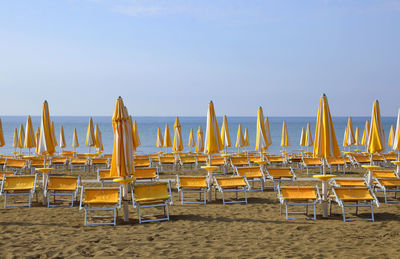 Chairs and tables on beach against sky