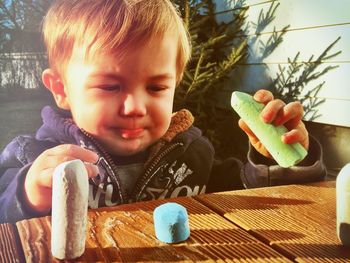 Close-up of innocent boy playing with chalks at wooden table