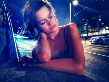 Young woman looking down while sitting in car at night