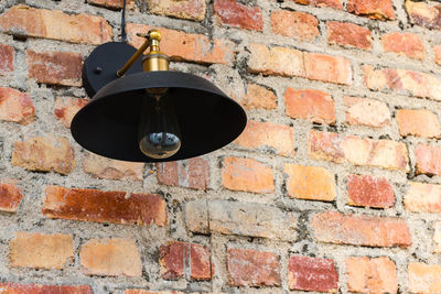 Low angle view of electric lamp on brick wall