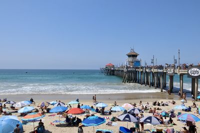 People at beach against clear blue sky