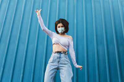 Portrait of young woman standing against blue wall