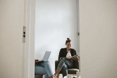 Young woman using mobile phone while sitting on chair