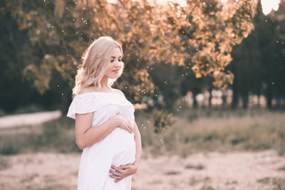 Pregnant woman with eyes closed standing at park