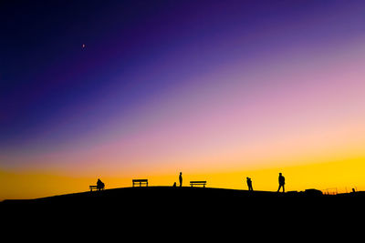 Silhouette man standing on landscape against clear sky during sunset