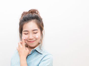 Portrait of smiling young woman against white background