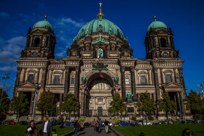 Tourists in front of church against cloudy sky