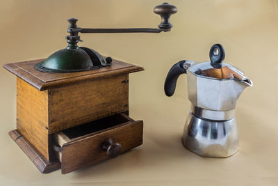 Close-up of coffee pot and grinder on beige background