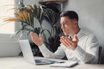 Young man using laptop while sitting on table