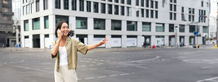 Portrait of young woman standing in city