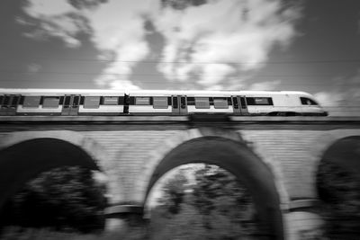 Train on bridge against sky in city