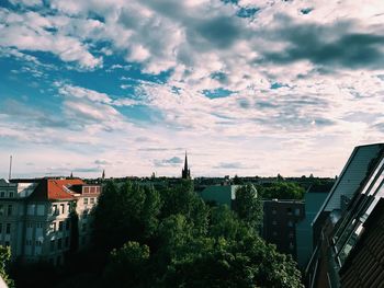 Trees and houses against sky in city