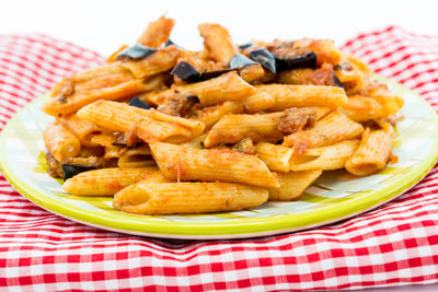 Close-up of fresh penne pasta served in plate on napkin against white background