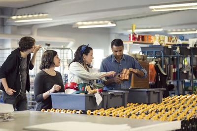 Volunteers analyzing objects in crate on production line at workshop