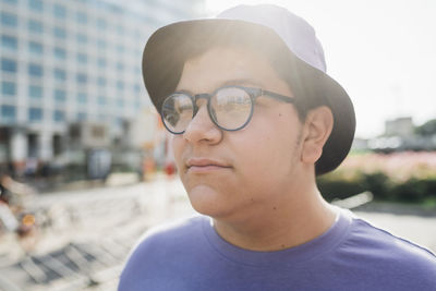 Thoughtful teenage boy with eyeglasses on sunny day