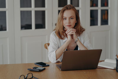 Businesswoman using laptop while sitting on table