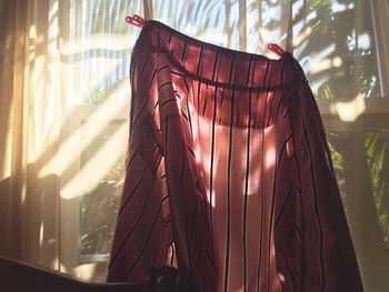 Close-up of shirt hanging on curtain at home