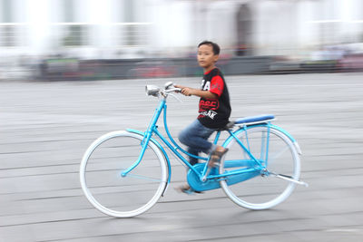 Side view of young woman riding bicycle on city
