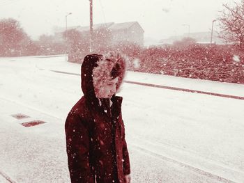 Man on snow covered road against sky