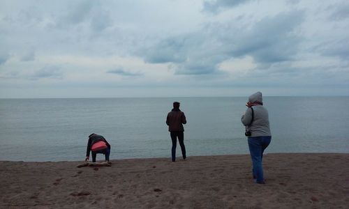 Friends standing on beach against sky