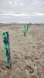 Wooden posts on beach against sky