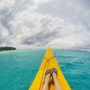 Low section of person on sea against sky