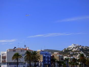 Mid distant view of helicopter over townscape against sky during sunny day