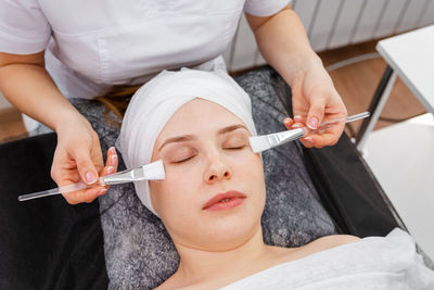 Beautician applying clay face mask on woman face. beautician working