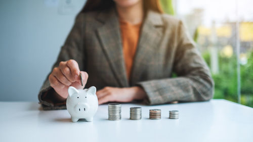 Midsection of woman holding piggy bank on table