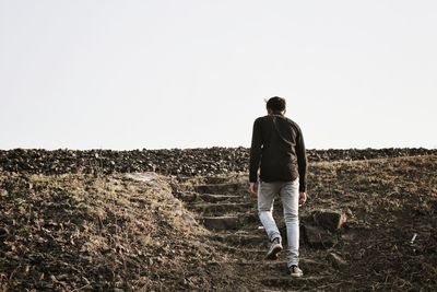 Rear view of young moving up on steps against clear sky