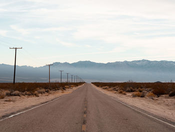 Road leading towards mountains against sky