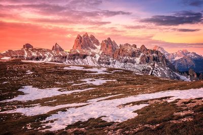 Snow covered landscape against sky during sunset