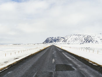 Road by snowcapped mountain against sky