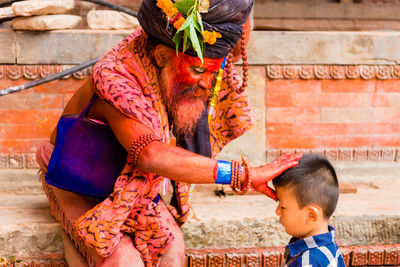 Side view of a boy holding baby outdoors