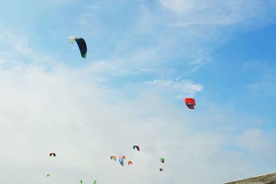 Low angle view of hot air balloons flying against cloudy sky