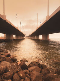 Bridge over river against sky during sunset