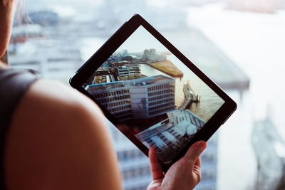 Cropped image of woman photographing with digital tablet