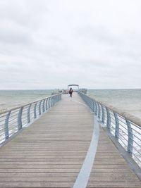 Rear view of pier over sea against sky