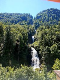 Scenic view of waterfall in forest against sky