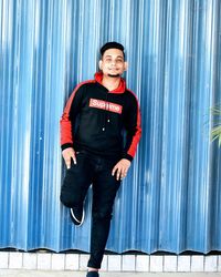 Portrait of smiling young man standing against wall