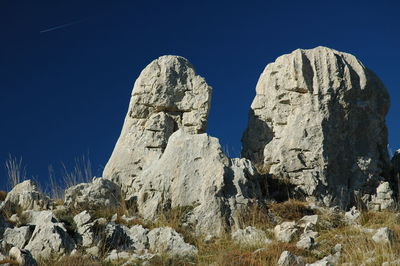 Low angle view of rocks against blue sky