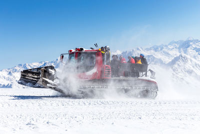 People on snow covered mountain against clear blue sky