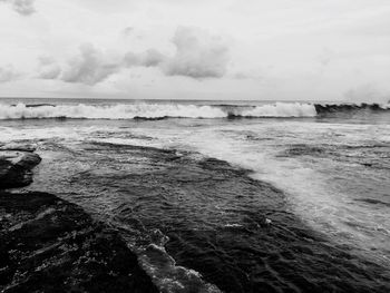 View of calm beach against cloudy sky