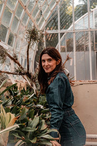 Portrait of young woman standing against window. greenhouse. botanic garden 