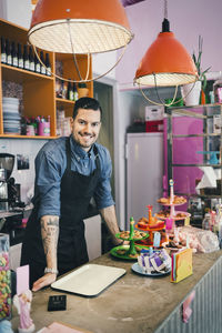 Portrait of confident male barista standing at counter