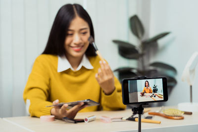 Young woman using mobile phone while sitting on table