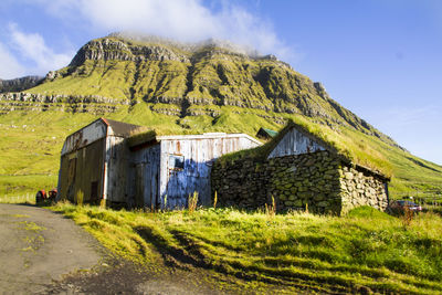 House on field by mountain against sky