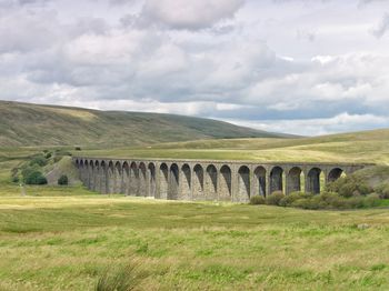 View of bridge over landscape against cloudy sky