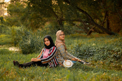 Full length of a smiling young woman sitting on land