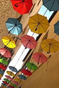 Low angle view of multi colored umbrellas hanging against sky